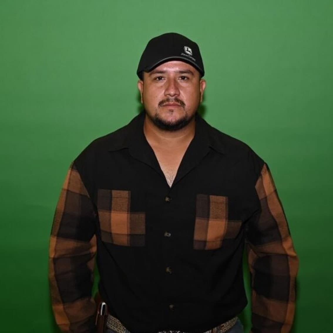 Rogelio García vistiendo una gorra nerga y una camisa a cuadros naranja.