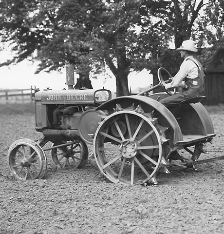 Un Tractor Histórico John Deere de Uso General "GP" tira de un Rotocultivador John Deere n° 7 en el Campo