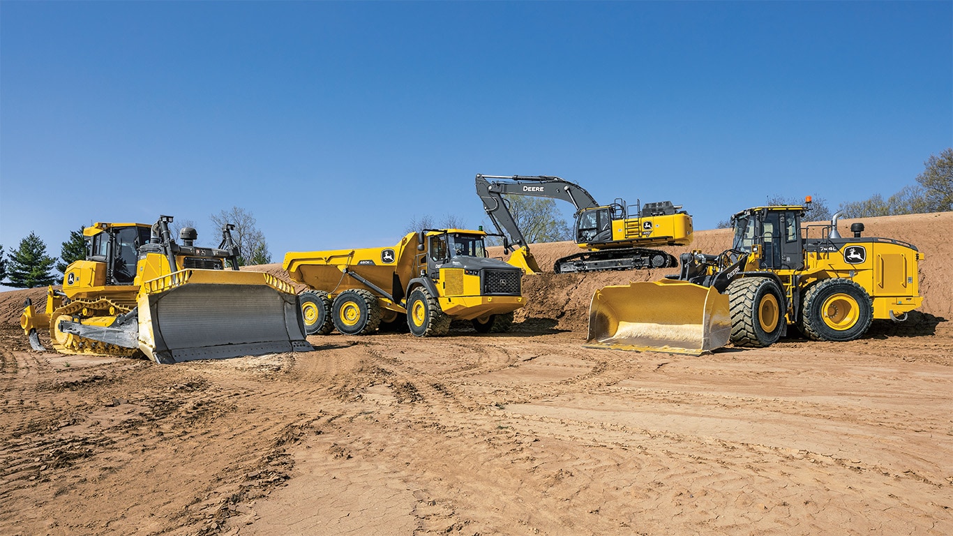 Varios vehículos de construcción Deere en terrenos sucios