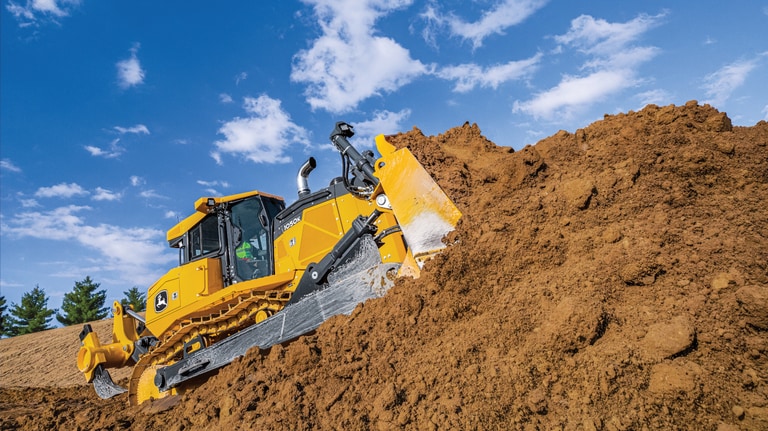 Un bulldozer 1050K empuja tierra en una colina en un lugar de trabajo.