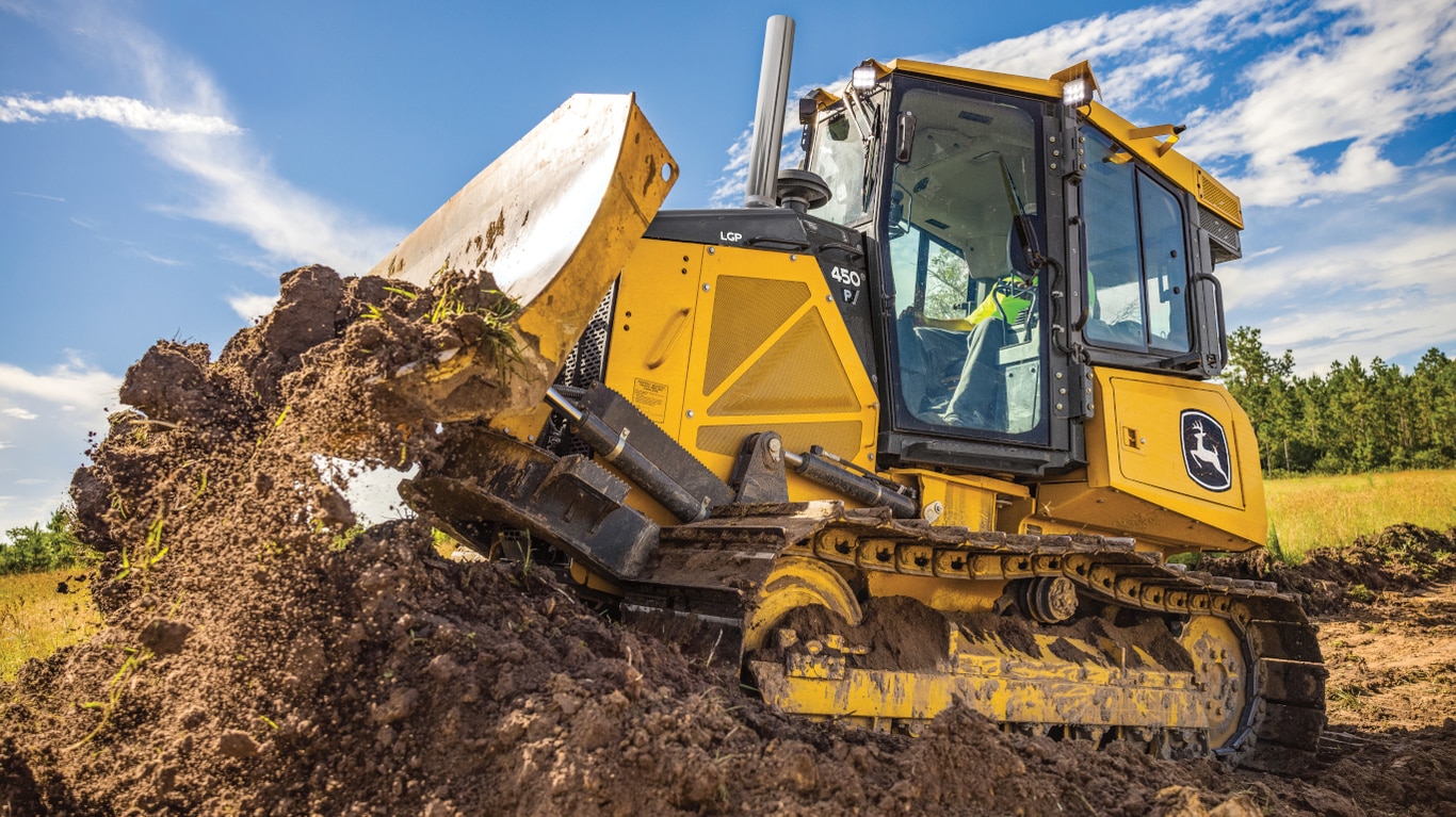 Vista lateral de un bulldozer 450P moviendo tierra.