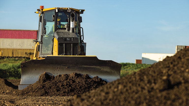 Vista frontal de un bulldozer 550P empujando la suciedad hacia un depósito.