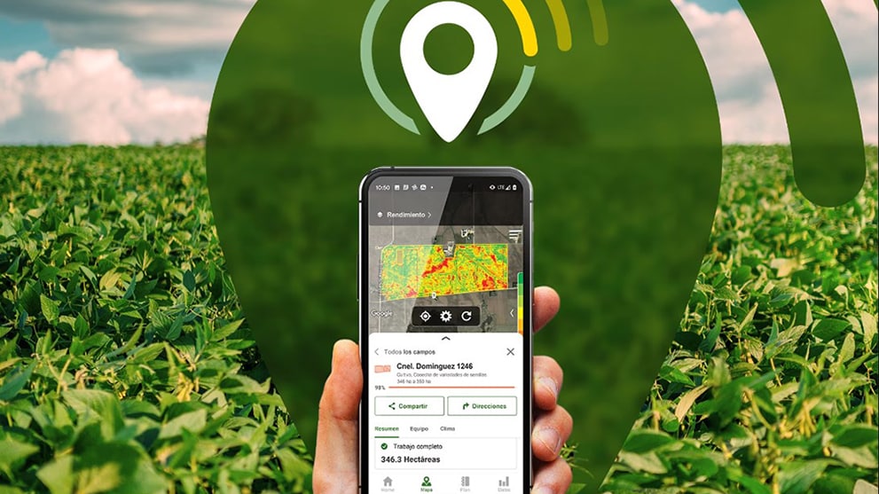 Una mano sosteniendo un teléfono inteligente en el que se puede ver abierta la aplicación Operations Center con detalles de un campo. De fondo está el logotipo de la aplicación Operations Center, un cultivo y el cielo azul con nubes.