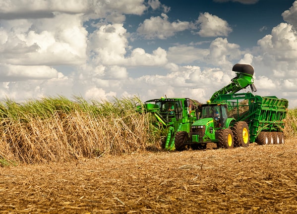 Cosechadora de Caña CH570 en el campo con tractor John Deere.