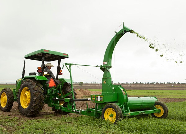 Picadora de forraje 972 en el campo con tractor John Deere.