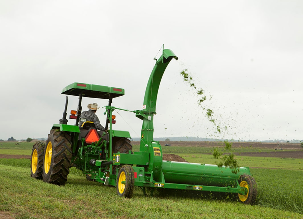 Picadora de forraje 972 en el campo con tractor John Deere.