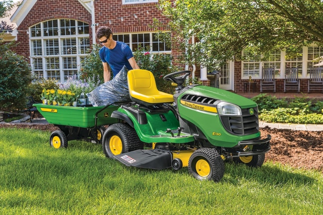 Tractor de Jardín E130 con carro de utilidad de John Deere.