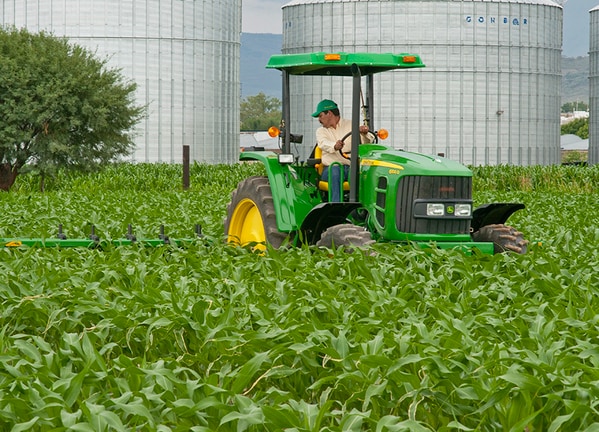 Cultivador 812 en el campo con tractor John Deere.