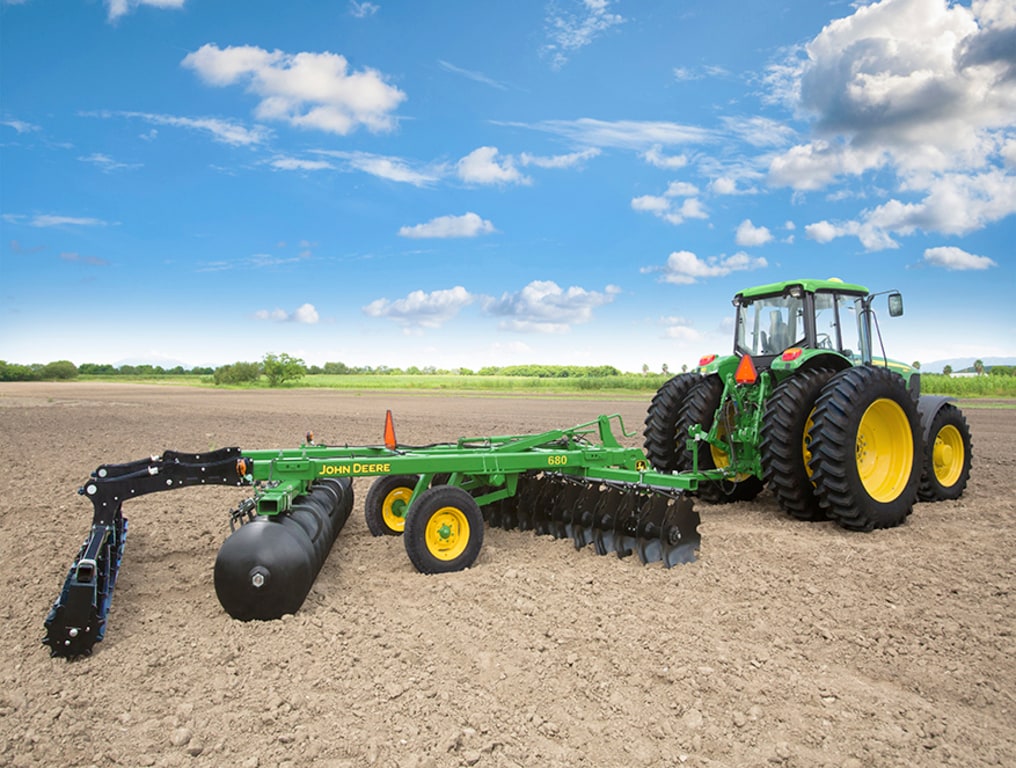 Rastra 680 en el campo con tractor John Deere.