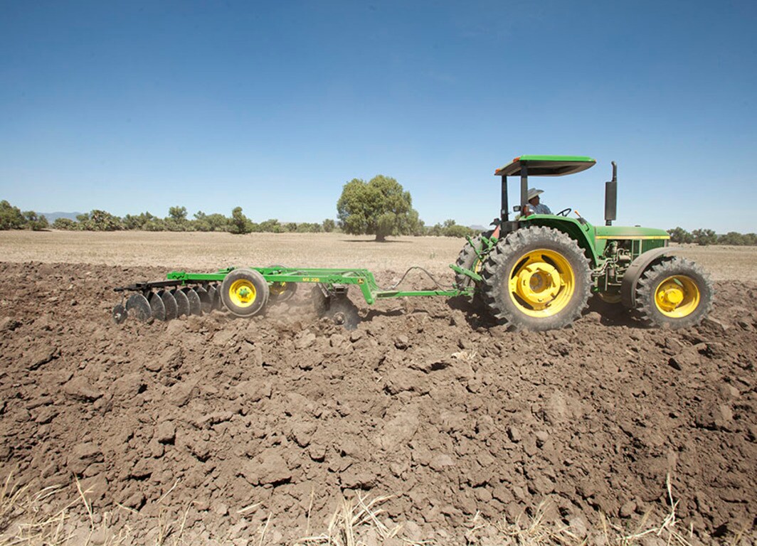 Vista lateral Rastra MX225 con tractor John Deere.