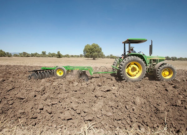 Vista lateral Rastra MX225 con tractor John Deere.