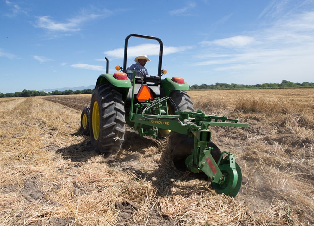 Arado de Disco 635 en el campo con tractor John Deere.