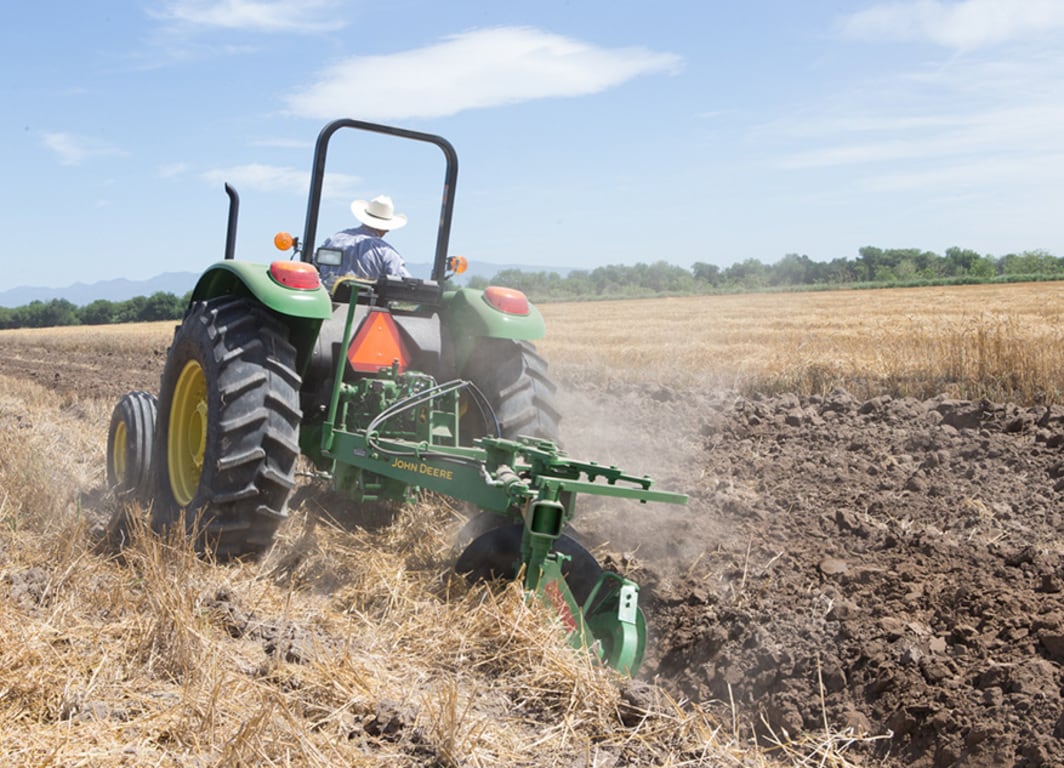 Arado de Disco 635 en el campo con tractor John Deere.