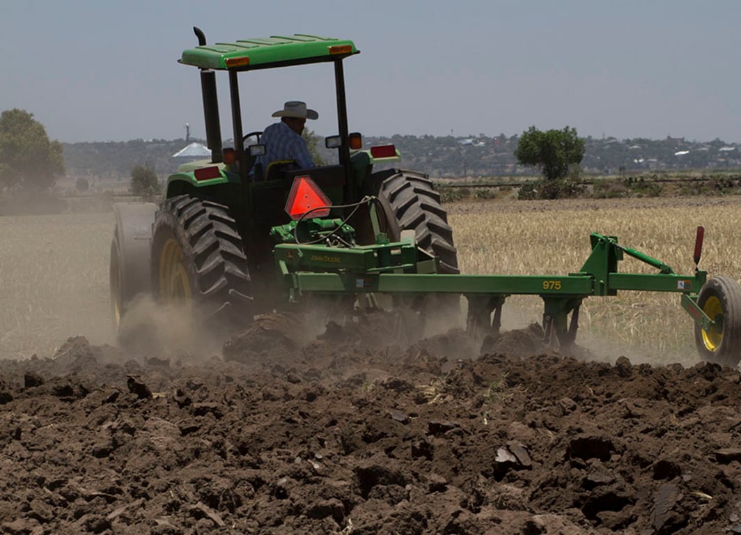 Arado de vertedera 975 en el campo con tractor John Deere.