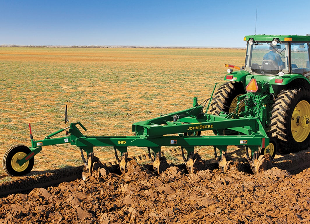 Arado de vertedera 995 en el campo con tractor John Deere.