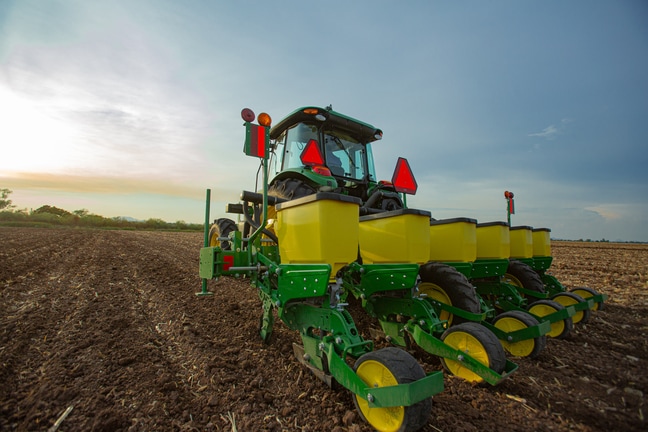 Imagen de tractor 6140E vista desde atrás mientras trabaja con sembradora