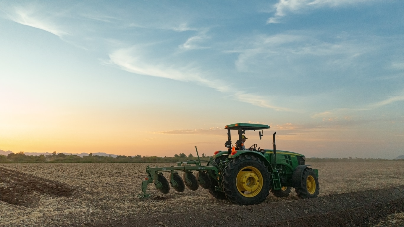 Tracot 6120E con el arado levantado mientras gira al final del campo de cultivo, de fondo el cielo azul a punto de comenzar el atardecer.