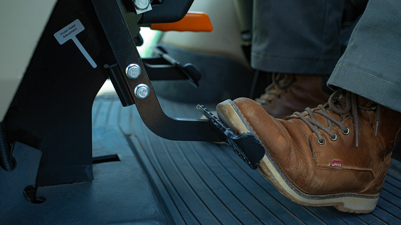 pie de técnico en botas presionando el pedal del embrague